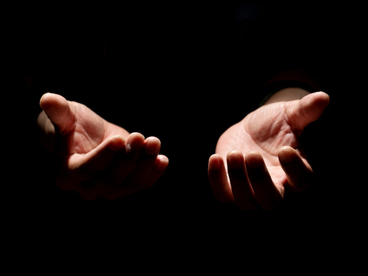 Manos abiertas ofreciendo, sobre fondo oscuro